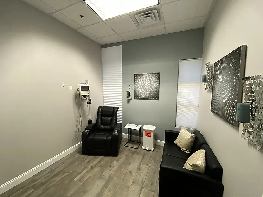 Clinic treatment room with a black recliner, sofa and abstract wall art
