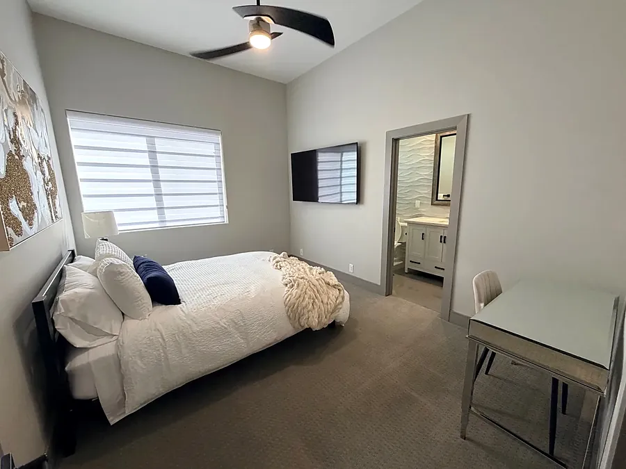 Bedroom at the house with white bedding, navy cushions and an armchair by the window