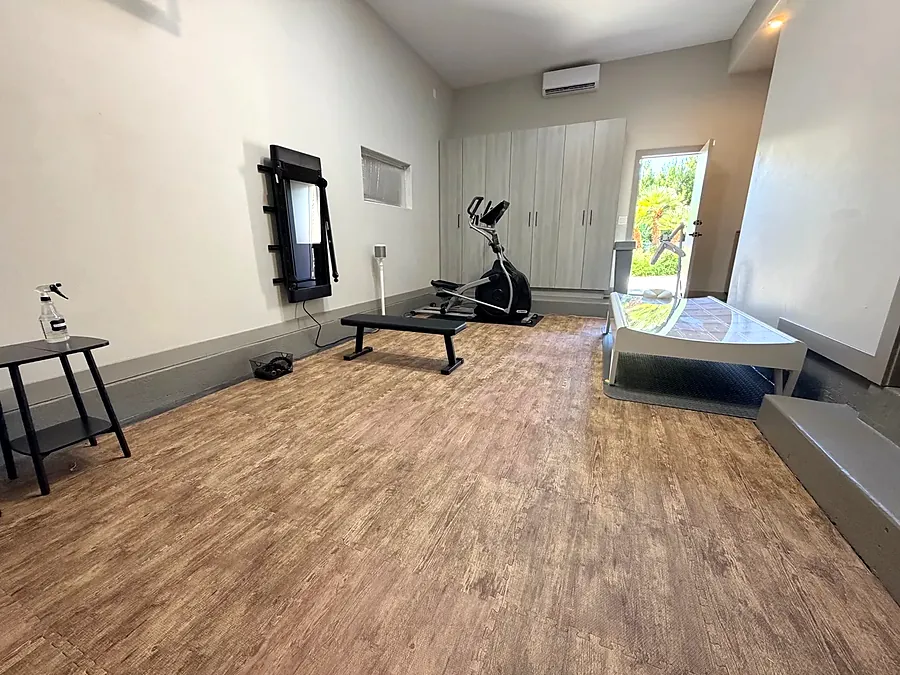 Exercise room with a wood floor, exercise bike, bench and mirror