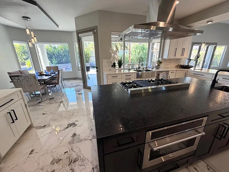 Kitchen with a dark island, gas hob and dining table beside garden windows