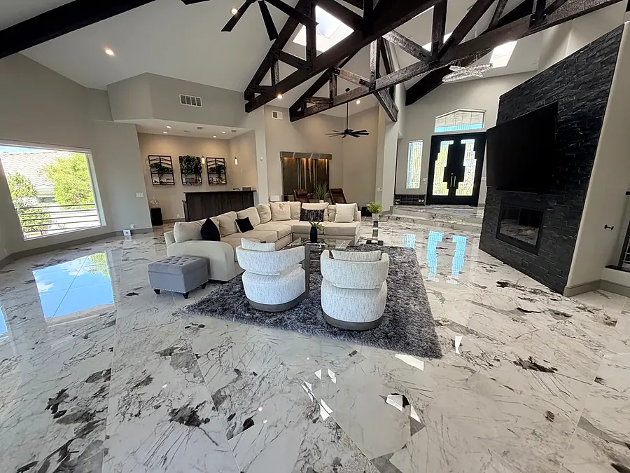 Double-height living room with timber beams, white sofas and a large window