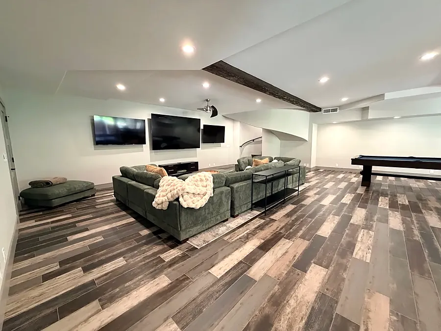 Media room with green sectional sofas and two wall TVs